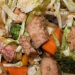 A closeup of the finished stir fry of pork and raw vegetables